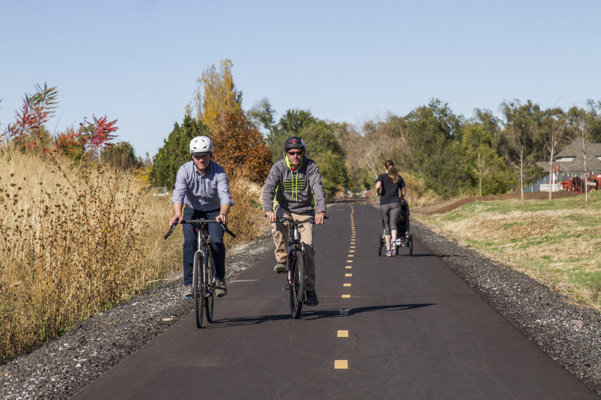 Bicyclists and a jogger with a stroller utilize the Golden Spoke trail network.